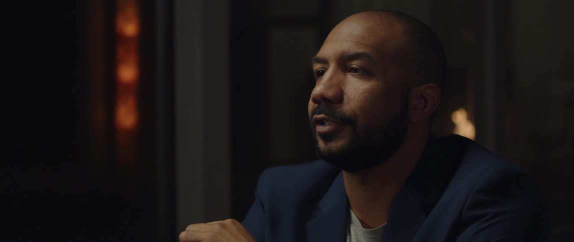 A man is sitting in a room and wearing a suit
