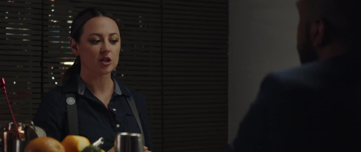 A bartender is using her hands as she talks to a customer