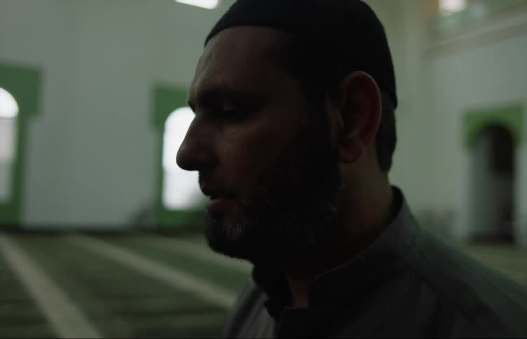 Muslim man with gray shirt prays at the mosque
