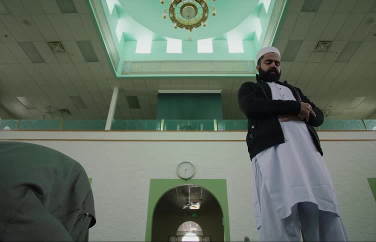 Two men stand up from praying in a mosque