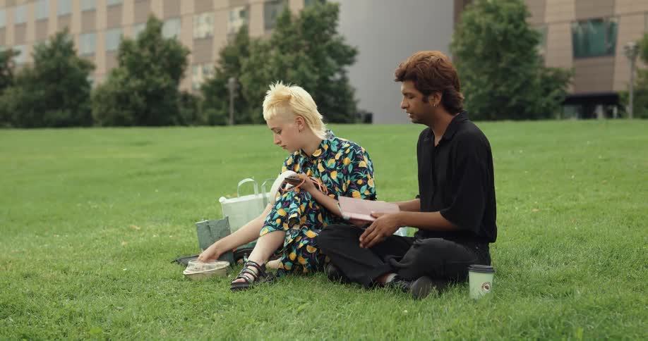 Two friends are hanging out in the grass and talking