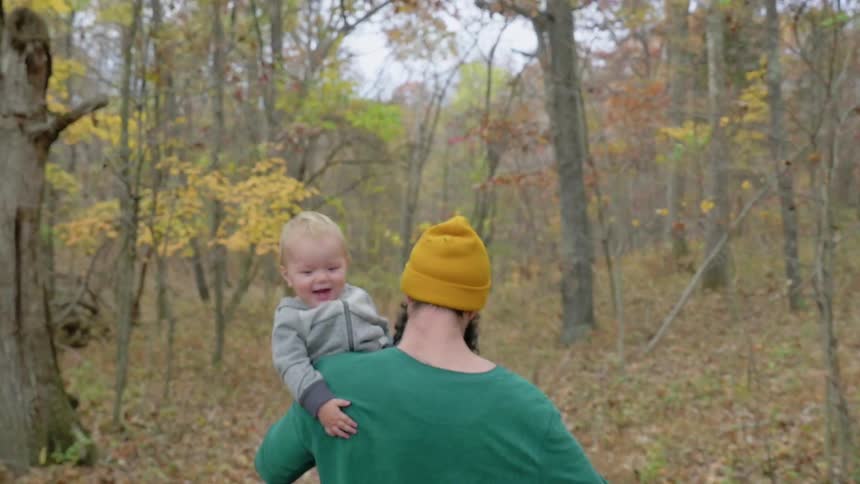 A man carries a boy on his shoulder through the forest