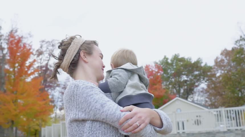 A child walks past leaves into a woman's arms