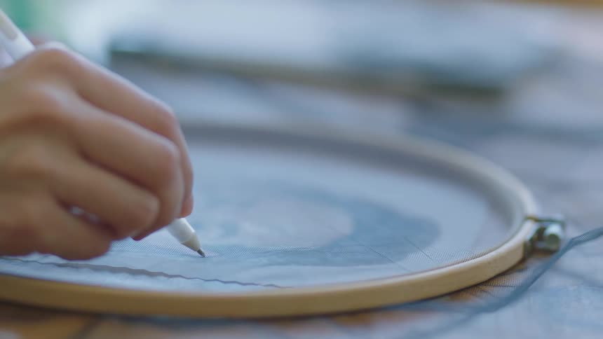 A woman traces over an embroidery hoop