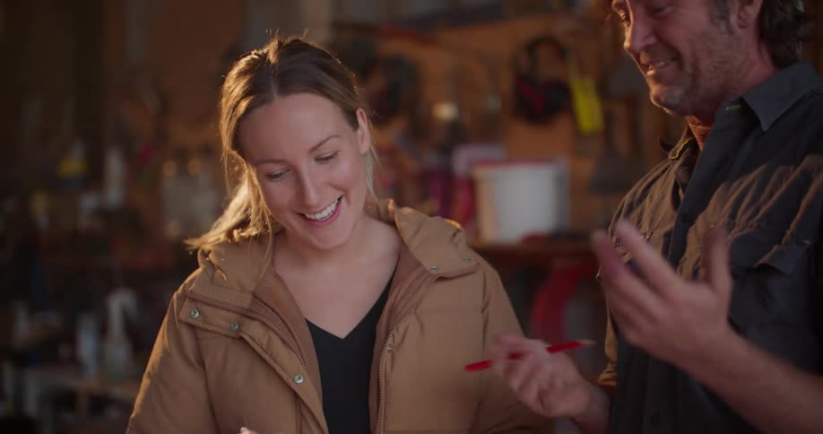 A man and woman chat while standing in a garage