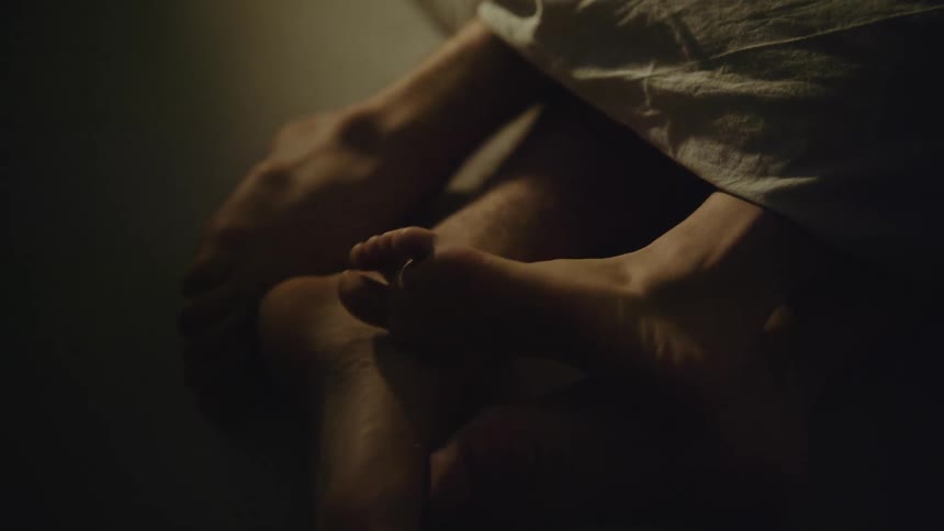 Woman rubbing her uncovered feet against her boyfriends feet in the bed