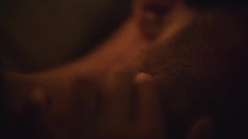 A womans hand slowly grazes and taps down a mans face and neck in a sensual way