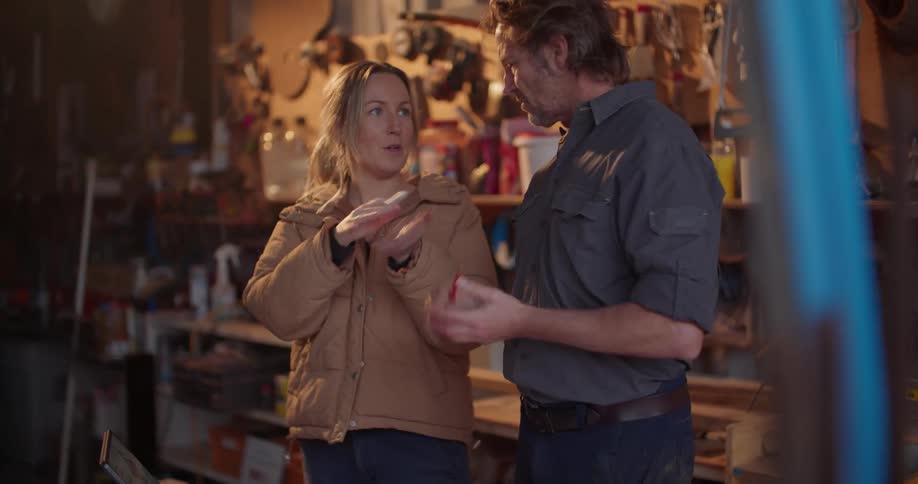Man and woman discuss plans on computer while standing in workshop