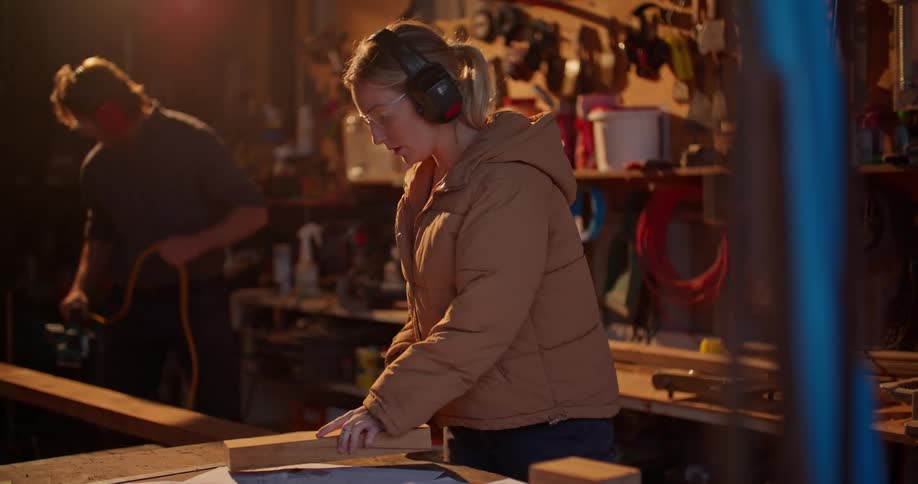 A man and woman sand wood in a garage