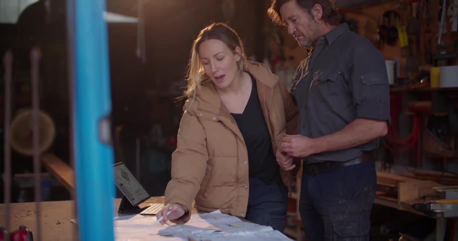 Contractors go over blueprints while working in a garage