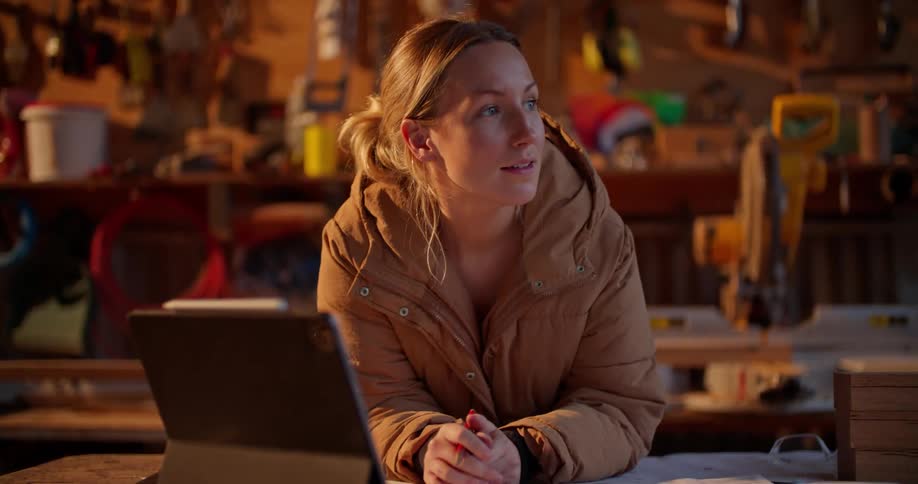 A woman leans on a table as she talks on a video call on a tablet