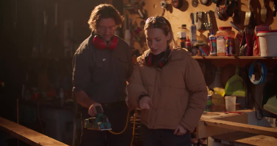 Two people are using tools to fix something indoors