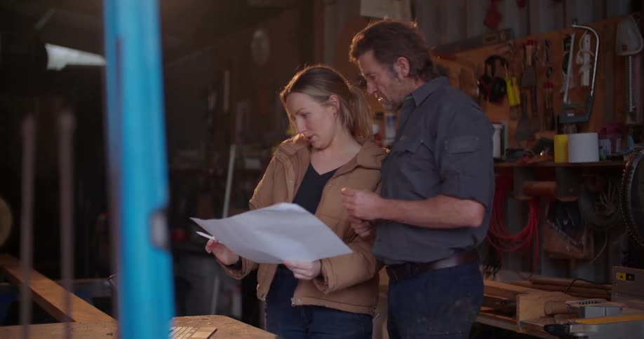 Contractors go over blueprints while standing in a garage
