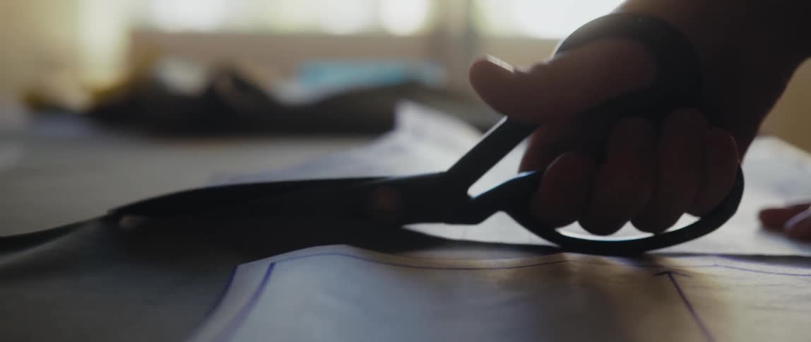 A womans hands can be seen cutting a pattern with scissors