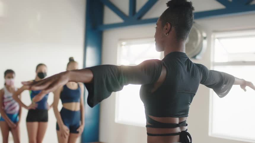 A ballet instructor is teaching a group of young girls in a studio