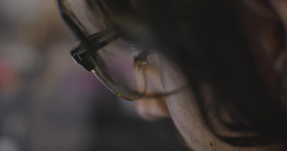 A person wearing glasses blinks while looking down