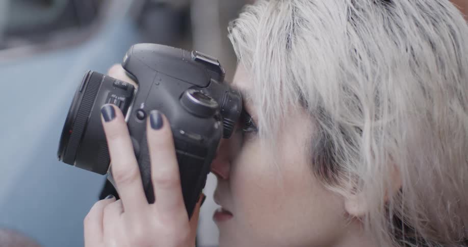 A woman looks through a camera