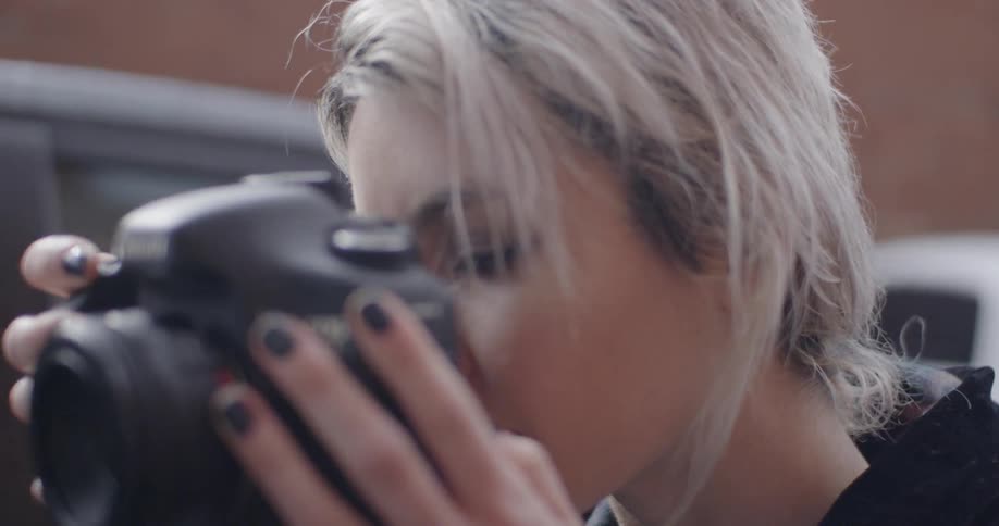 A woman takes a photograph with a digital camera and then reviews the image