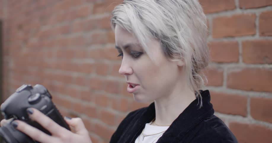 A woman examines a camera and goes to take a photograph