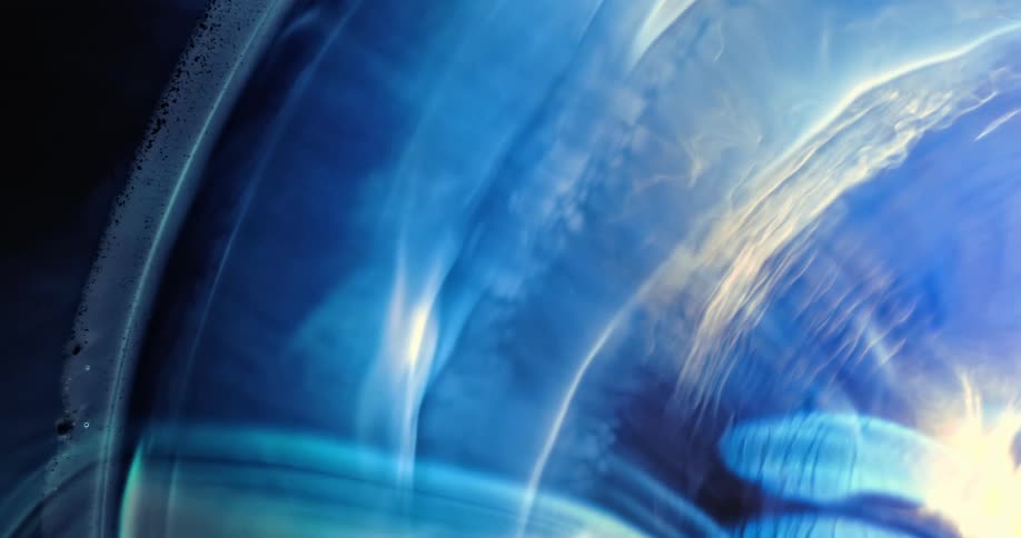 Waves of colorful bright blue and white smoke floating over a black background