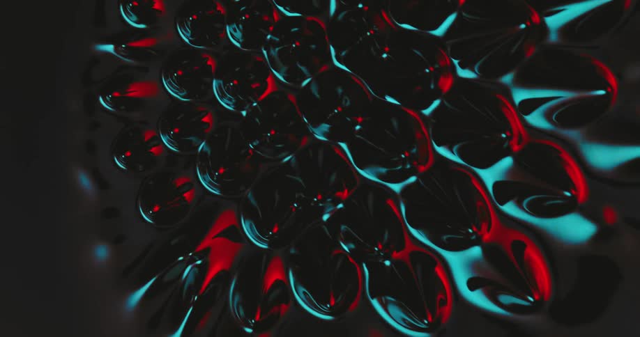 Top down view of spikes growing out of a black liquid reflecting red and blue lights