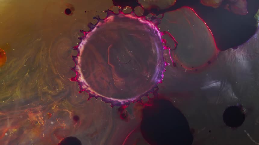 Rings of bright liquid colorful ink floating and flowing over an abstract background