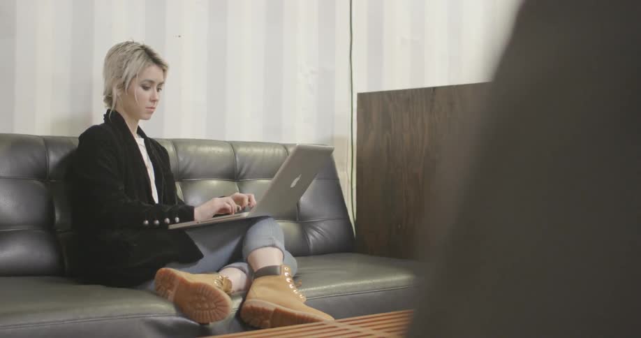 A woman in a black jacket types on a laptop