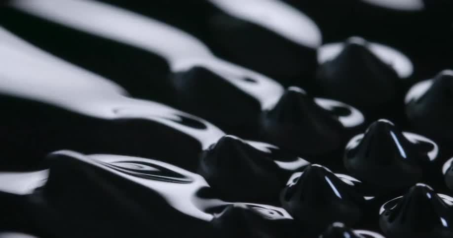 Ring of spikes rise and move over a dark reflective liquid