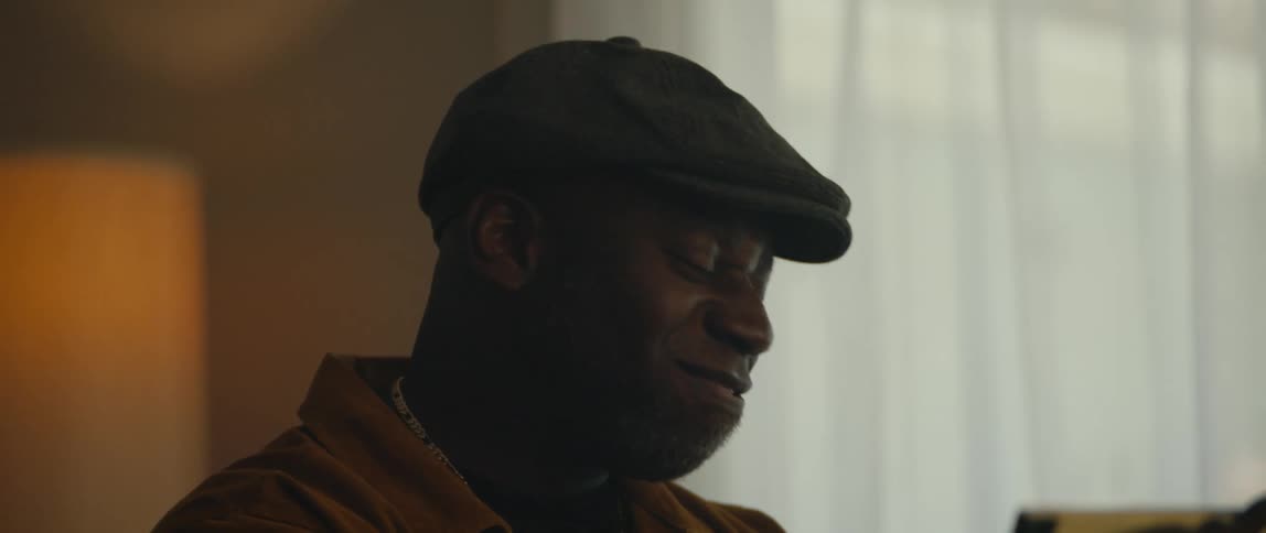 A young black man is sitting down and singing