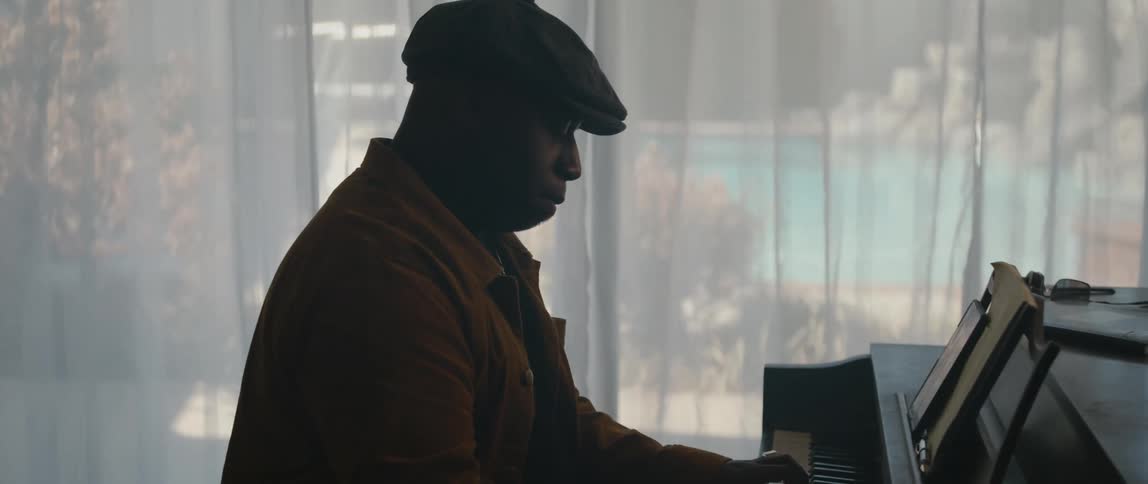 A black man plays a piano at home