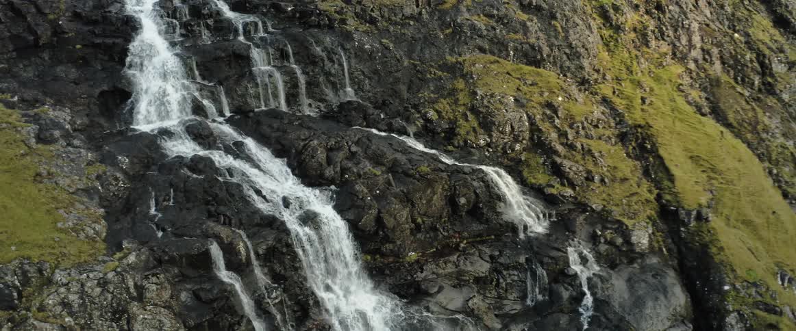 A waterfall is flowing from a mountain in spring