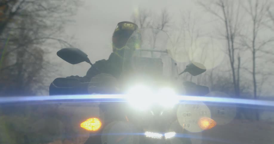 A man is sitting on a motorcycle while its raining outdoors