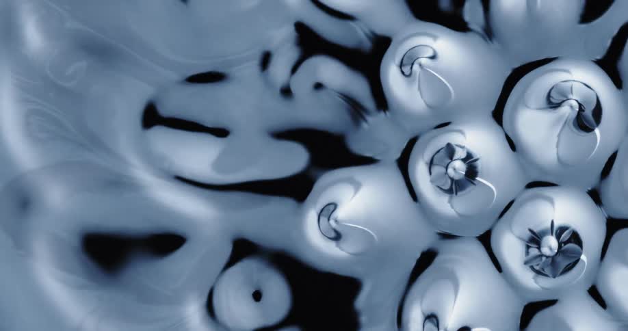 Peaks bubbles and patterns flow and form on the surface of dark liquid
