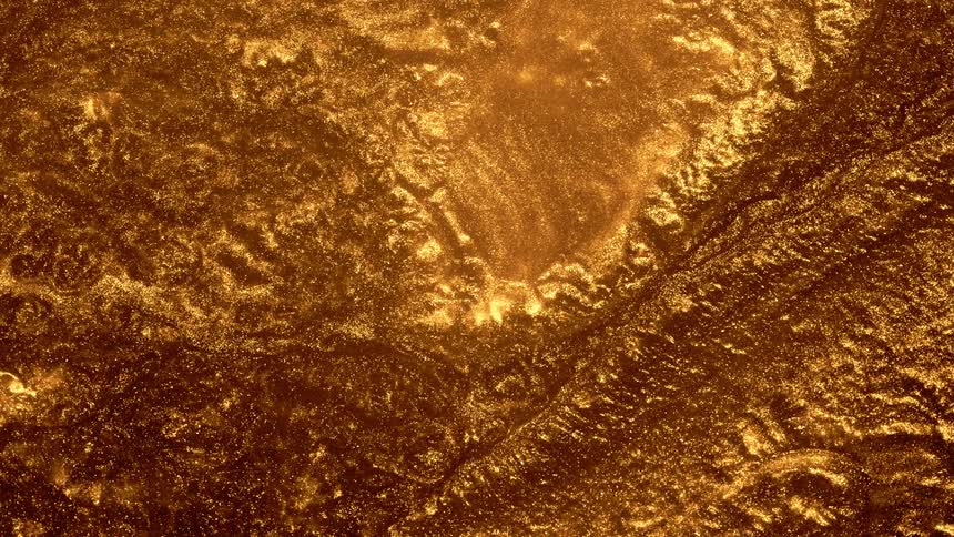 A shiny gold substance rolls and twists into itself