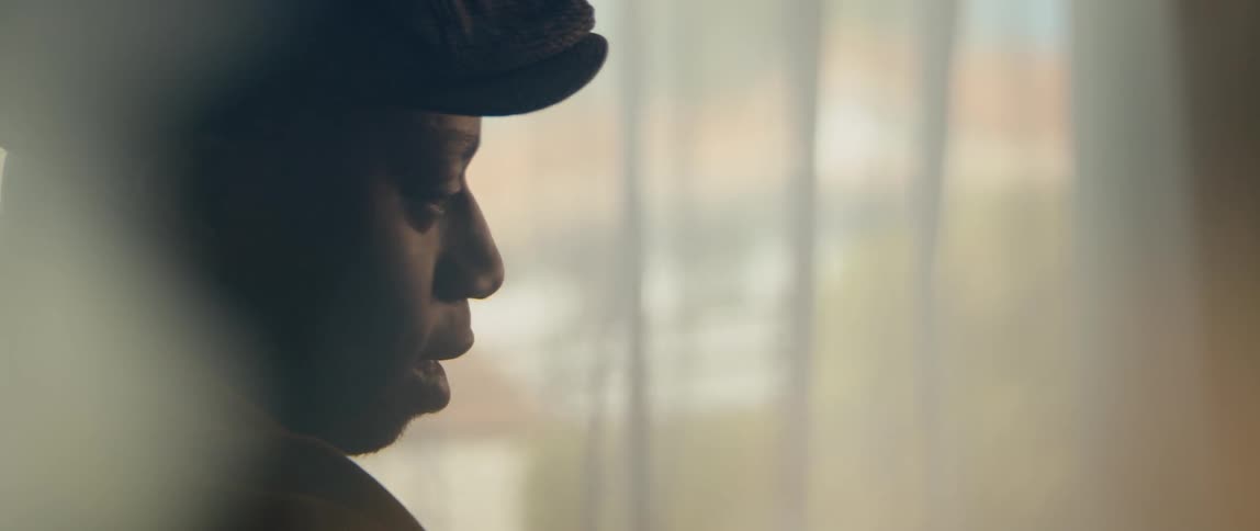 A young black man is sitting down and singing