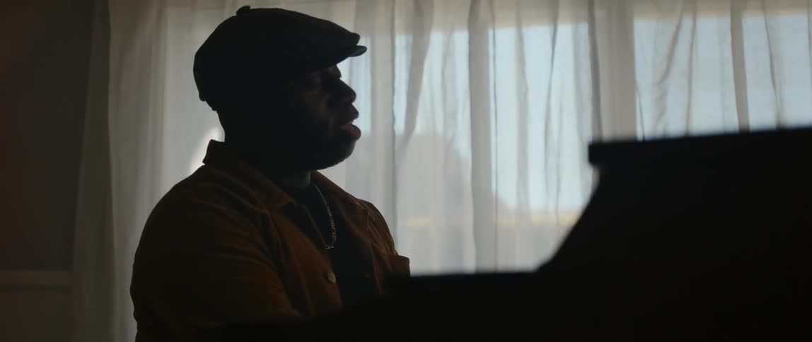 A man singing while playing a piano at home with his eyes closed