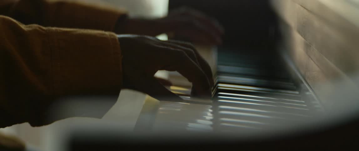 A man is sitting indoors and playing a piano