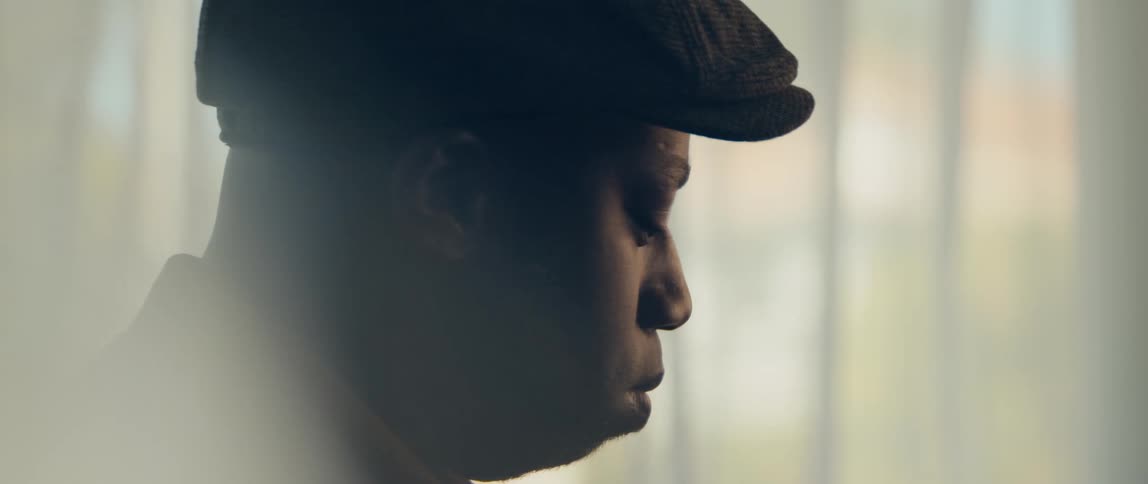 A young black man is sitting down in the living room