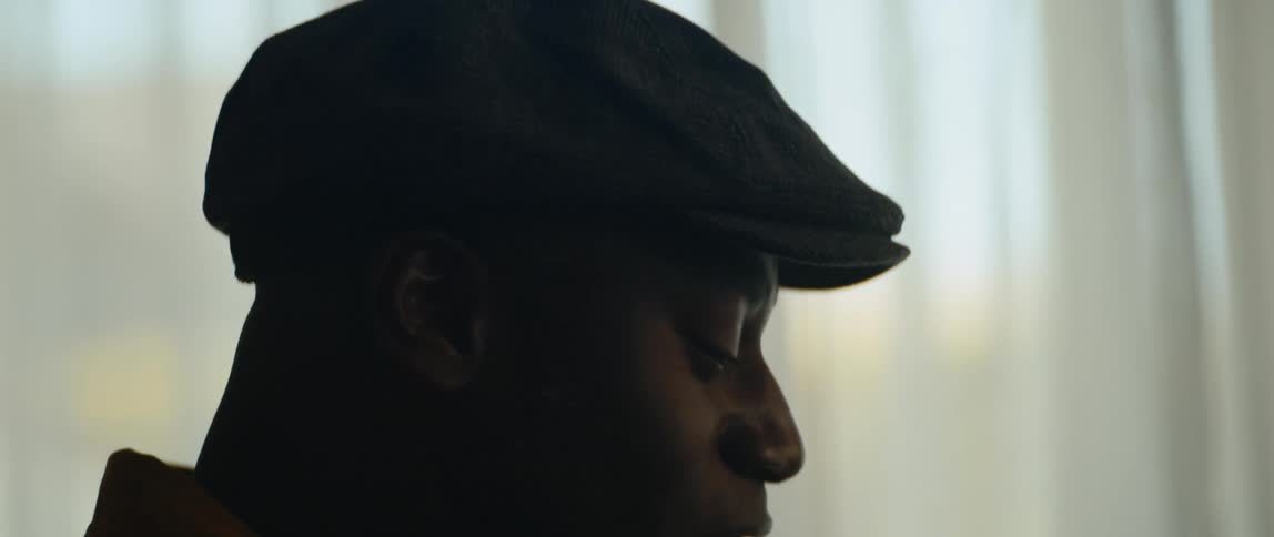 A man is wearing a hat and singing indoors