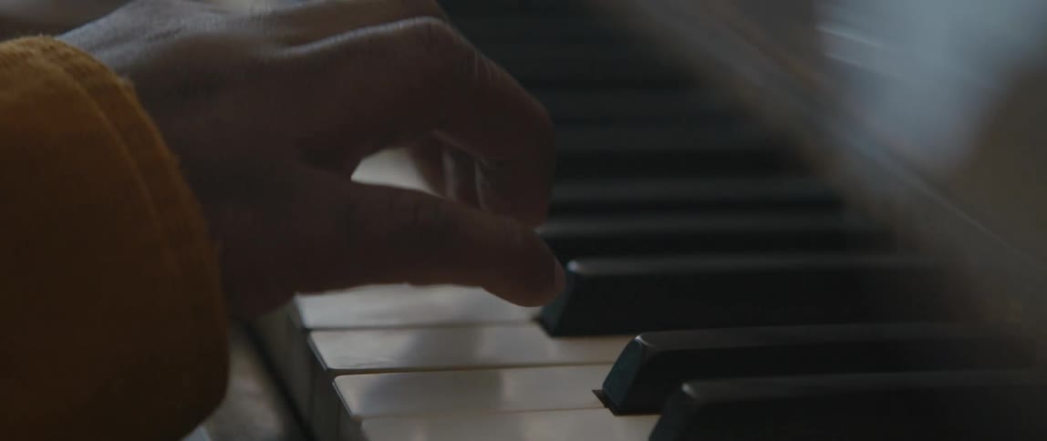 A black man is playing the piano in the living room