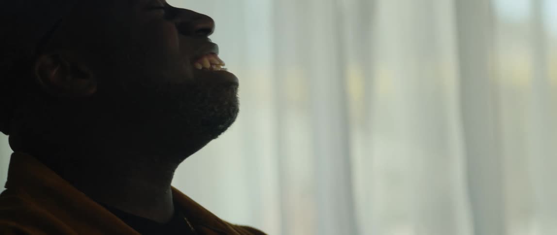 A young black man is sitting down and singing