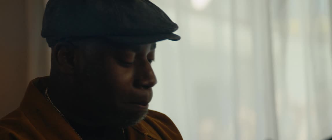 A young black man is sitting down and singing