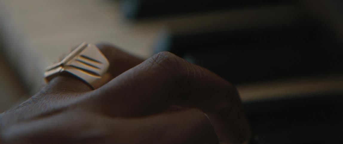Fingers of a black woman wearing a golden ring playing a piano