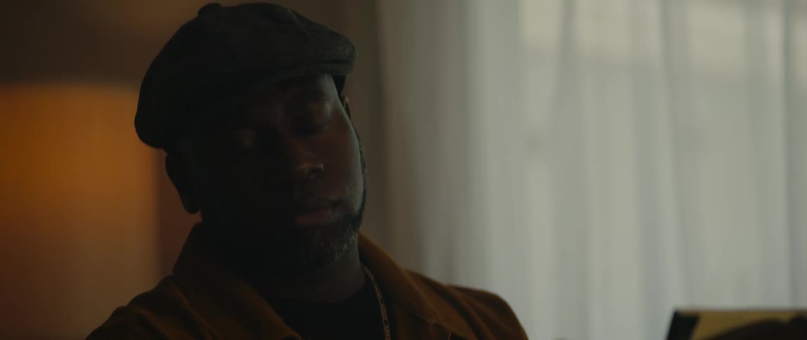 A man is sitting in a room in his house near a window