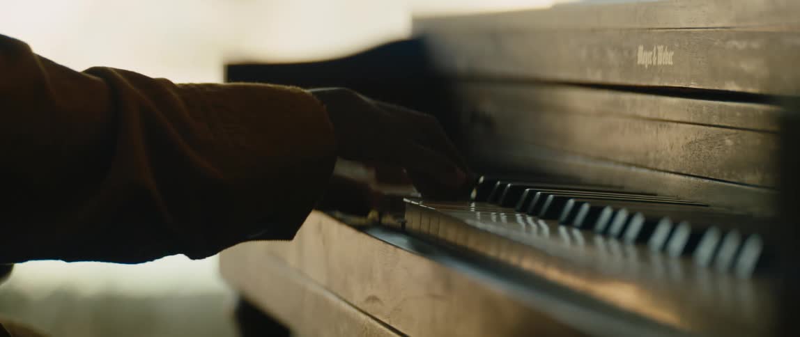 A black man is playing the piano inside the room