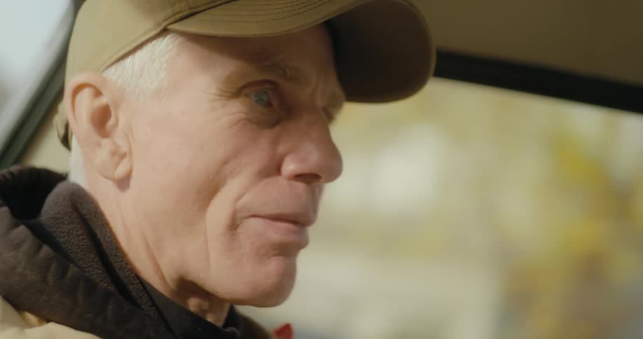 An elderly man is in a car driving a vehicle