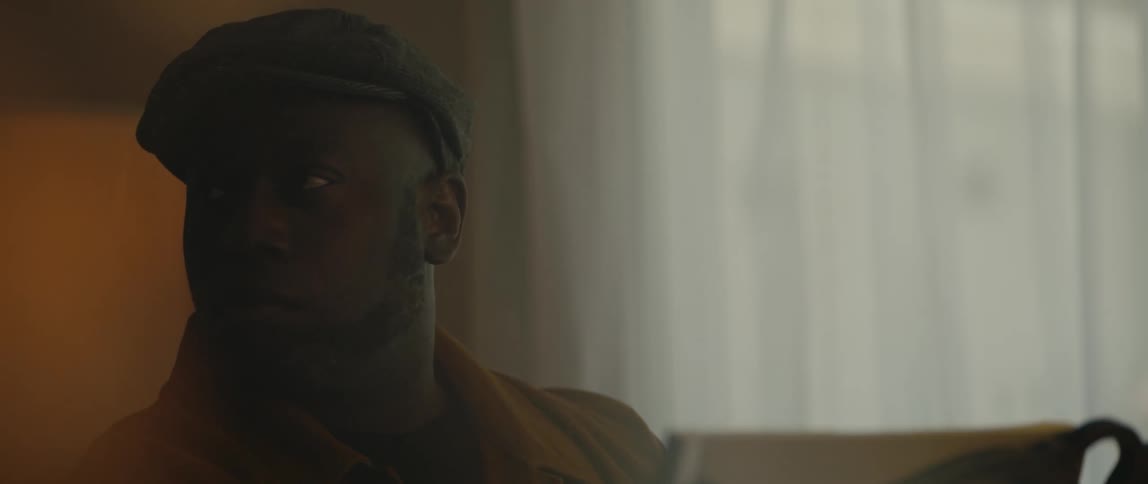 A young black man is wearing a hat and sitting down