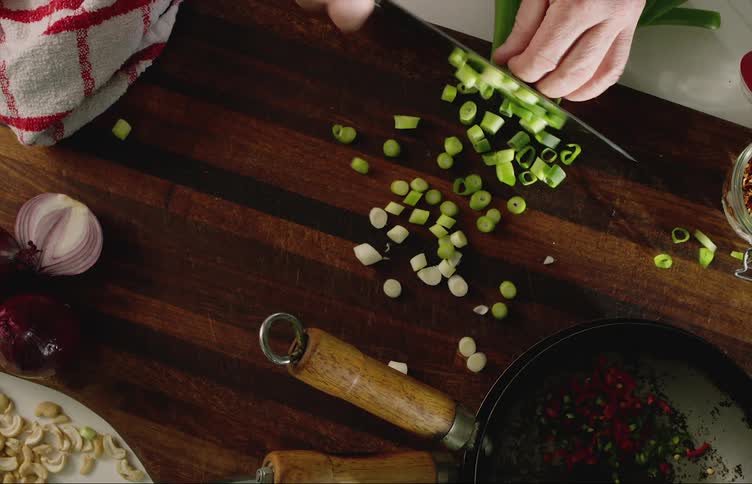 Chopping green onions rapidly then gathering and tossing in skillet