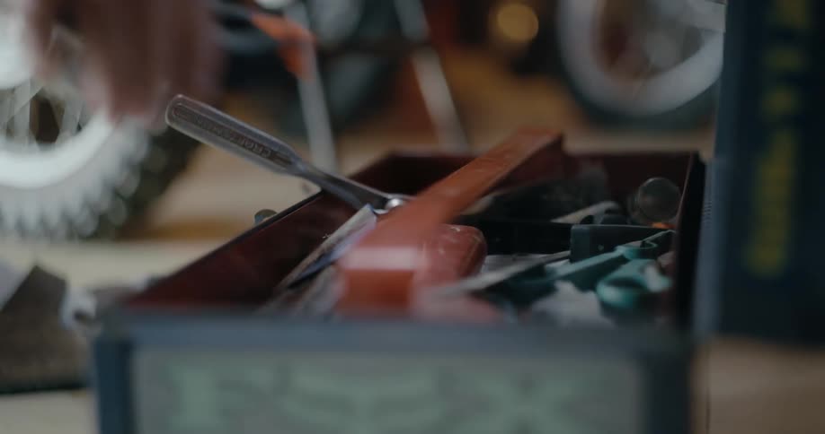 Man picks up tools from a toolbox laying on a garage floor