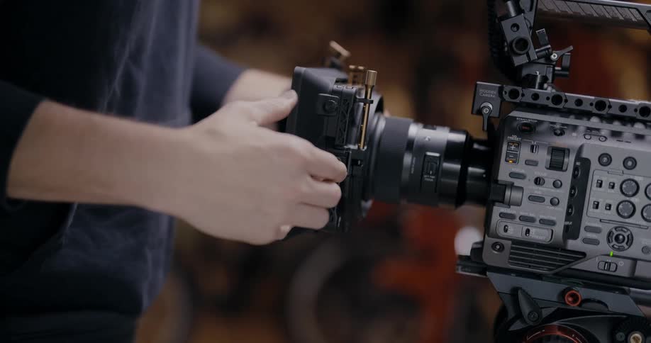 A person placing a lens onto a video camera